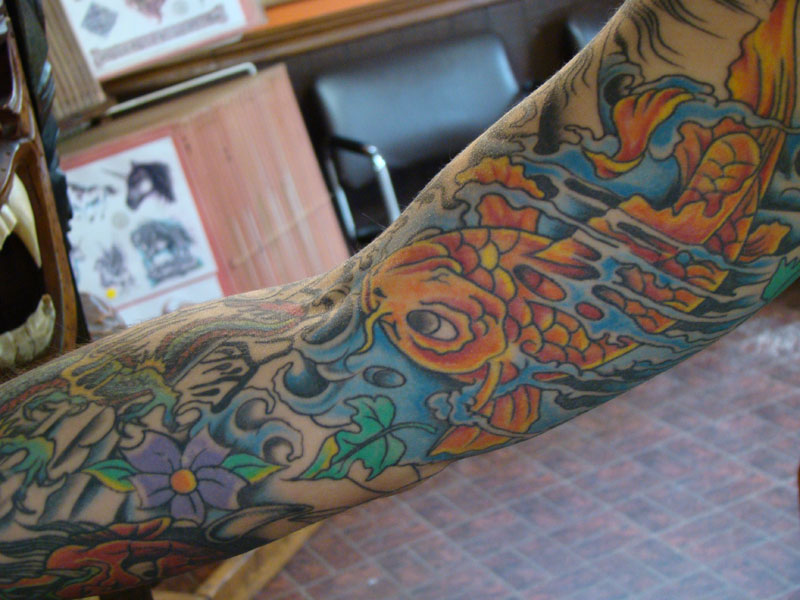 This is an oldschool full sleeve tattoo featuring koi fish dragons