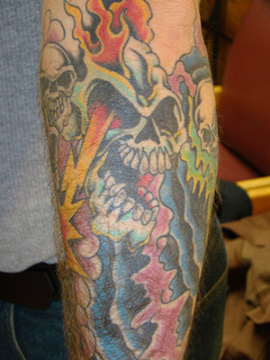  sleeve tattoo features lots of evil looking skulls wrapped in flames and 