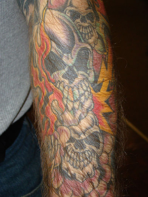 Buddha and temple upper arm tattoo. On his shoulder are cherry blossoms and